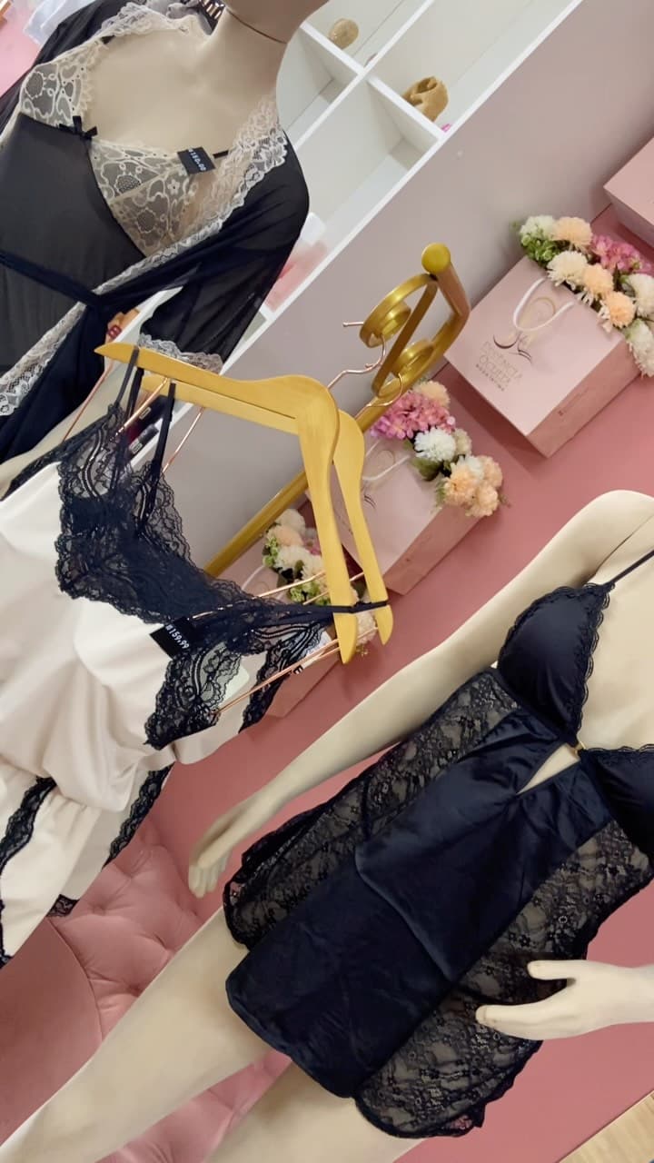 Arara dourada com conjunto e camisola de renda preta ao lado de robe off-white